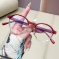 Gafas redondas retro anti-luz azul con montura degradada roja y transparente en la mano - Degradado burdeos