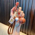 Sports themed keychain featuring a basketball and golf club charm with brown strap - Coffee