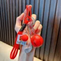 Red sports keychain featuring basketball, golf ball and club charms on a red braided rope - Red