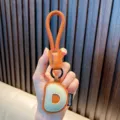 Llavero de cuero con la letra D del alfabeto en naranja y beige metal - Letra D