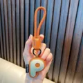 Faux leather letter P keychain with orange braided strap and green accent - Letter P
