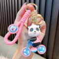Cute cartoon panda riding a blue bicycle PVC keychain accessory with pink braided strap - Pink