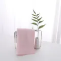 Detailed close-up view of a soft pink latex face towel on a minimalist gold stand - 30*30cm / Pink
