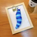Vibrant blue gradient articulating slug fidget toy keychain with golden bell for bags. - Dark Blue