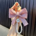 Elegant hand-beaded pearl keychain featuring a large pink ribbon bow and gold clasp - Pink