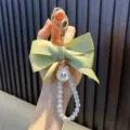 Handcrafted pearl bead keychain featuring a large light green fabric bow and gold charm - Apricot