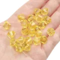 Vibrant yellow 10mm faceted bicone crystal beads for DIY jewelry making held on a palm - Diamond Pattern / 10mm Approx 46 Pcs / Yellow