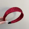 Gros plan sur un serre-tête en satin plissé bordeaux montrant la texture du tissu - Rouge