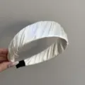 Détail rapproché d'un serre-tête large en satin plissé crème avec texture élégante - Beige
