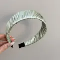 Nahaufnahme des eleganten, gefalteten Satin-Stirnbands in Salbeigrün mit hochwertiger Textur - Grün