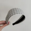 Vue détaillée d'un bandeau en tissu à larges bords à carreaux gris élégant tenu à la main. - Serre-Tête Grand Plaid Gris