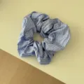 Dettaglio ravvicinato di uno scrunchie a scacchi blu e bianchi con morbida trama di tessuto - Elastico per capelli / Quadri Blu