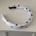 Detailed macro view of a white padded headband with black bow print and handmade tag - Padded Headband / White with Bowknot