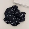 Detailed macro view of a stylish black scrunchie featuring white bow and floral prints - Scrunchie / Black Bow
