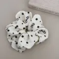 Detail shot of a chic white scrunchie with elegant black rose and bow prints. - Scrunchie / Beige Bow