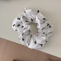Close-up of a white fabric scrunchie featuring a minimalist black bow print design - Scrunchie / White with Bowknot