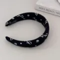 Close-up of black headband with white bow and rose patterns on a minimalist background. - Headband / Black Bow
