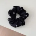 Close-up detail of a black fabric scrunchie with white bow-knot pattern - Scrunchie / Black Bow