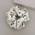 Detail view of a white scrunchie featuring elegant black floral and bow patterns on fabric - Waist-Curve Hair Scrunchy / Beige Bow