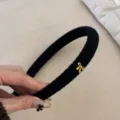 Elegante zwarte gebreide haarband met een verfijnde goudkleurige strik bedel. - Gouden Tag Strik / Zwart