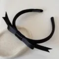 Primer plano de una diadema de raso negro con lazo y etiqueta hecha a mano en el interior - Negro
