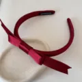Vista detallada de una diadema de satén rojo vino con elegante lazo y etiqueta de hecho a mano - Rojo