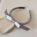 Detalle de diadema de satén plateado con lazo que muestra la etiqueta de hecho a mano - Gris