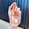 Handmade pink beaded phone strap featuring a cute bear charm and pink bow decoration - Pink