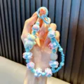 Cute blue beaded bear keychain with iridescent accents for phone or bags shown in hand - Blue