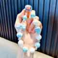 Blue and white iridescent beaded phone charm with a houndstooth cube and drip bow pendant - Blue