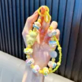 Vibrant yellow beaded phone strap featuring a cute cartoon bear charm and floral accents - Yellow
