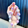 Handmade purple beaded phone charm with butterfly bow and checkered cube accent - Purple