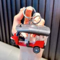 Miniature red pullback Tuk-Tuk taxi keychain toy model with silver ring held in hand - Red