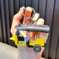 Miniature yellow Tuk Tuk tricycle model keychain held by hand for display and scale - Yellow
