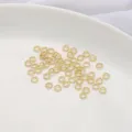 Vista macro de anillas abiertas retorcidas bañadas en oro 14K en plato blanco. - Juego de 20 Piezas / Diámetro 4mm / Lleno de Oro 14K