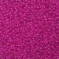 Macro primo piano di perline di semi verniciate magenta trasparente per creazioni fai da te - Rosso rosa