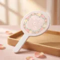 Close-up of elegant pink floral pattern on a white hand-held round vanity mirror detail - Peach Rose Pattern