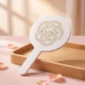 White handheld round makeup mirror with elegant gold knot pattern on pink background - Brocade Ruyi Pattern