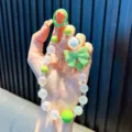 Attraktive grüne Perlen-Handykette mit einer großen Harzschleife und schillernden Perlen - Mit Handy-Pad / Grün