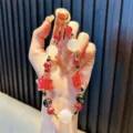 Funkelnder Handy-Anhänger mit roten Sternperlen, Kristallen und goldenem Schlüsselring - Farbwechselnder Katzenaugen-Stern / Inklusive Dichtung / Rot
