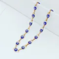 Detailed macro view of a gold plated stainless steel necklace with blue evil eye beads - Blue
