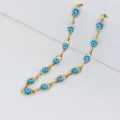 Dettaglio ravvicinato di una collana dorata in acciaio con grani occhio greco - Catena Color Acciaio / Celeste