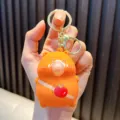 Simpatico portachiavi squishy capibara arancione che soffia una bolla con dettaglio mela - Arancione