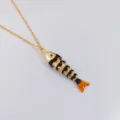 Primer plano detallado del colgante de pez articulado dorado con esmalte brillante - Negro