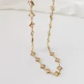 Primo piano dettagliato di una collana in acciaio inossidabile dorato con pietre a rombo champagne - 42+5cm / Colore loto