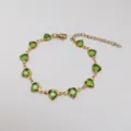 Primo piano dettagliato di un bracciale in vetro verde a forma di cuore in acciaio dorato - 17+5cm / Verde chiaro