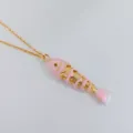 Primer plano de un colgante de pez articulado rosa en una cadena dorada fina. - Rosa Loto