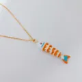 Detalle de collar de acero inoxidable dorado con un vibrante colgante de pez móvil esmaltado. - Blanco