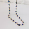 Detail of a stainless steel necklace featuring elegant square blue gemstones in gold - Blue
