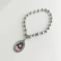 Detail of a silver stainless steel bead bracelet with a religious Jesus Christ oval pendant - Crucifixion Portrait